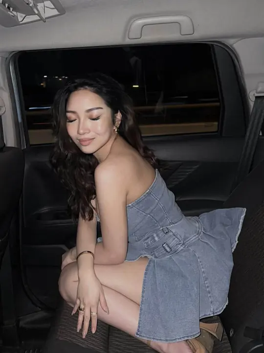 Debbie in a denim dress in a car.