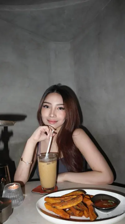 Debbie at a cafe table, smiling, with an iced coffee.